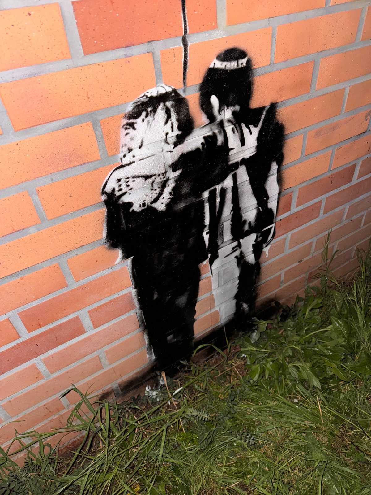 Gros plan de nuit sur le couple enlacé, noir et blanc, peint au pied du mur